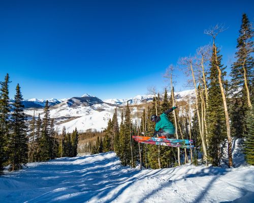 A person jumping in their skis on a bluebird day at Crested Butte skiing