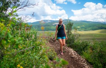 a woman hiking a trail in brush creek