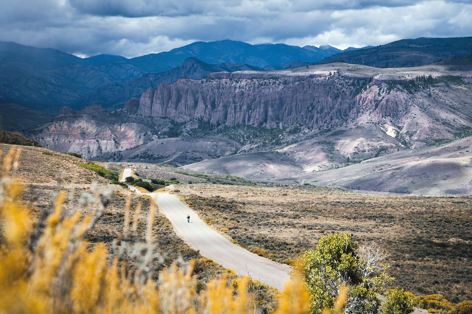Gravel biking near Blue Mesa Reservoir with gray clouds and spiny rock formations in the background.