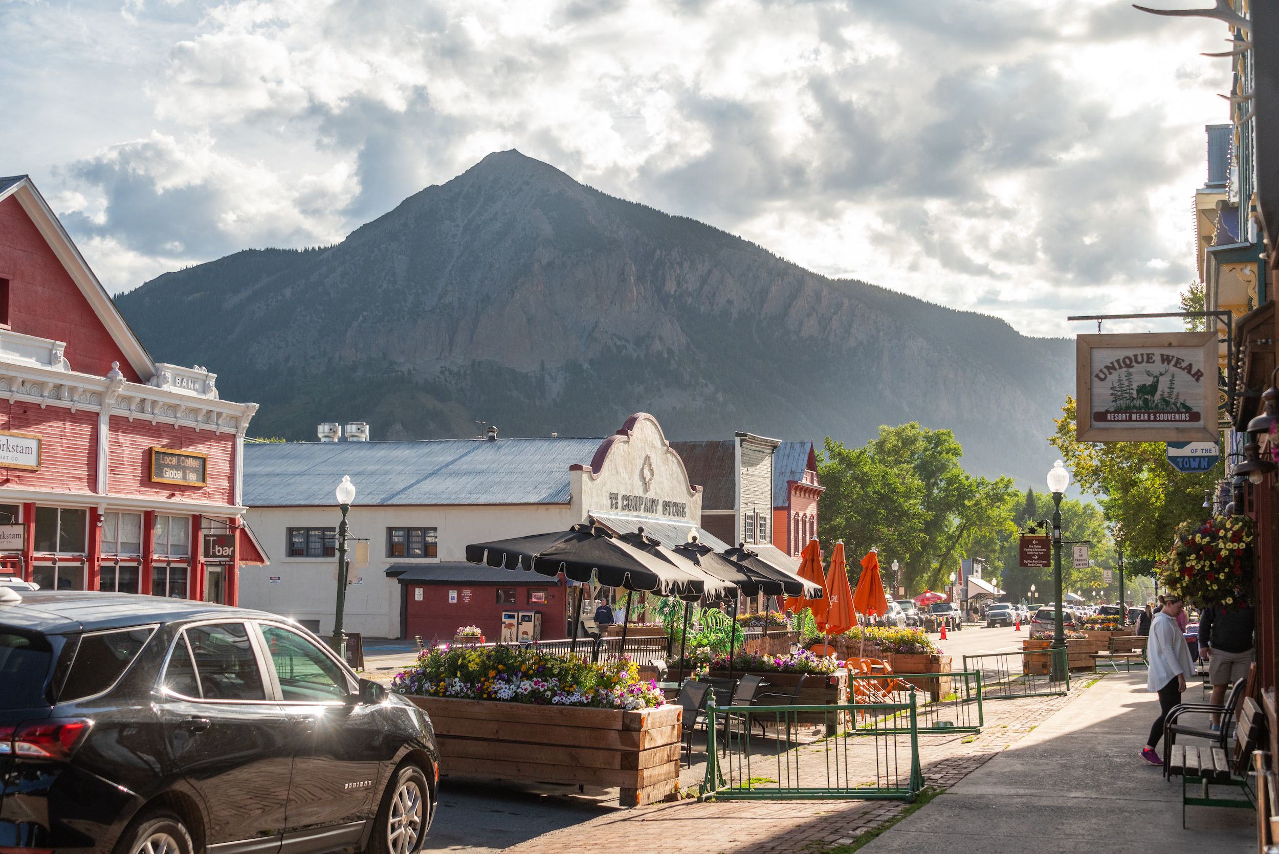 The view of a mountain peak hovering over a downtown street. This is Elk Ave in Crested Butte during summer