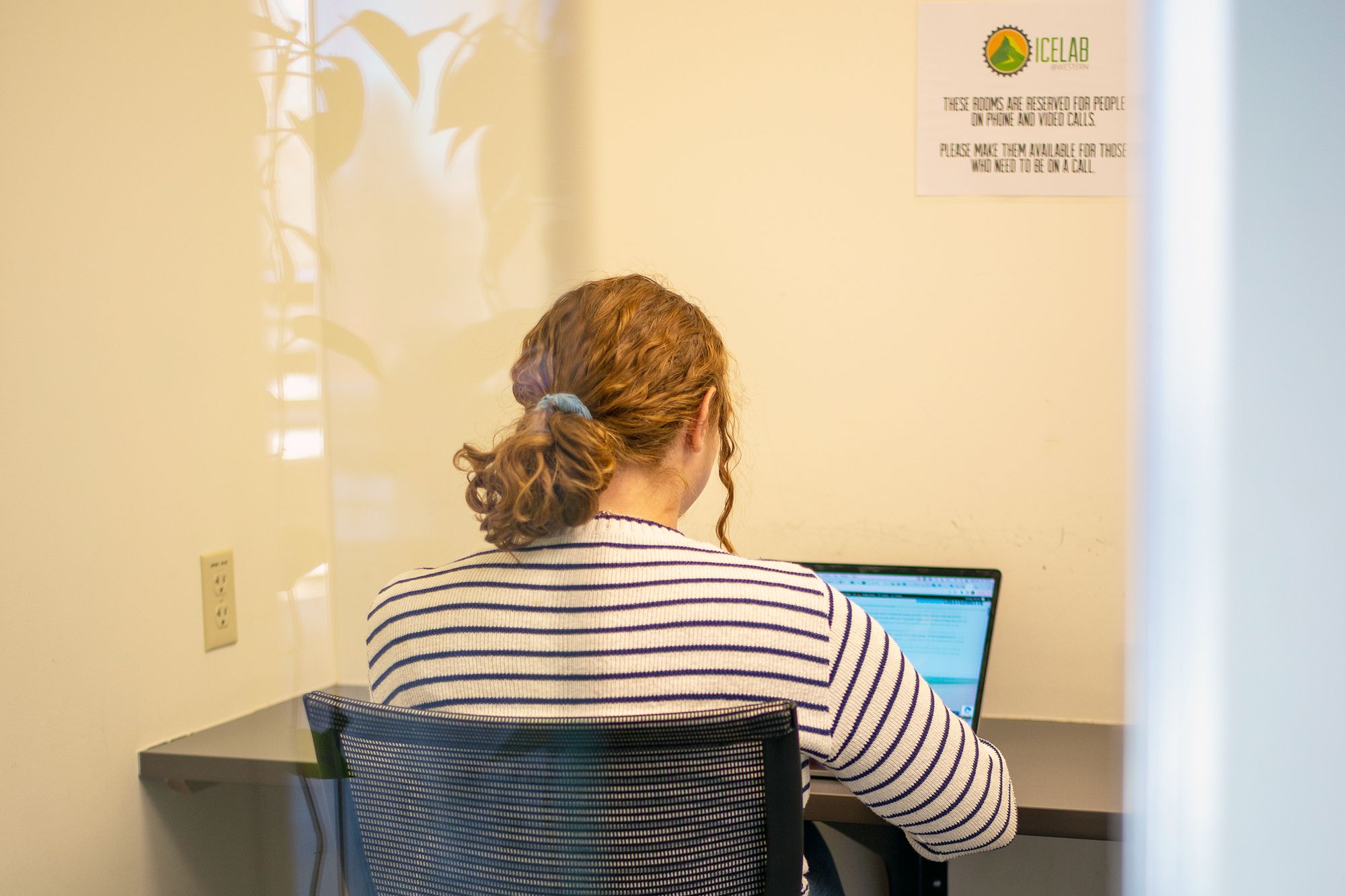 A woman works on her laptop in a phone room at the ICELab.