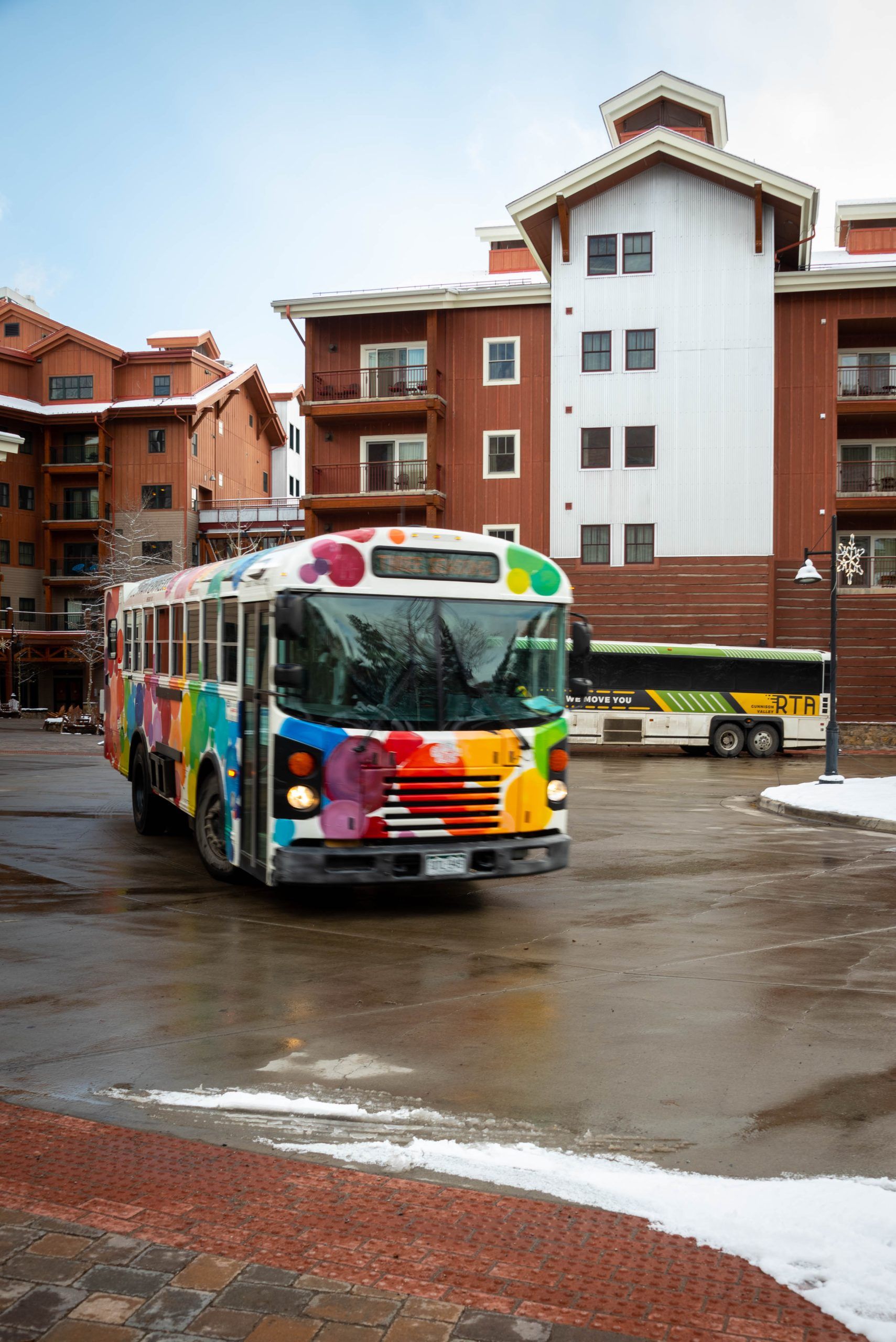The mountain express crested butte shuttle. A bus in front of a tall building. 