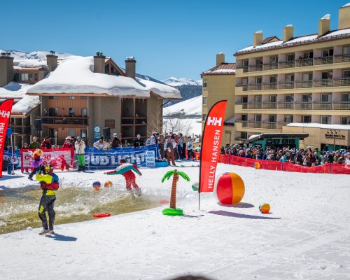 A person skis across a pond on skis. This event is the pond skim crested butte mountain resort