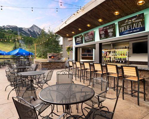 The Elevation Resort outdoor bar. Patio furniture with a mountain peak in the background next to a bar