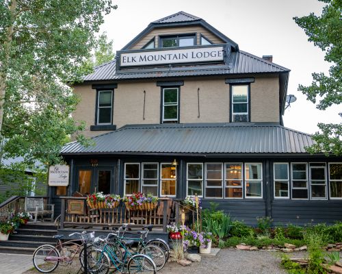 A lodge-style hotel with a bike rack and flower pots on the porch. This is one of the Crested Butte lodging options