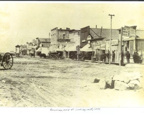 A sepia photo of downtown Gunnison from 1881. The street is dirt and the buildings are wooden and old