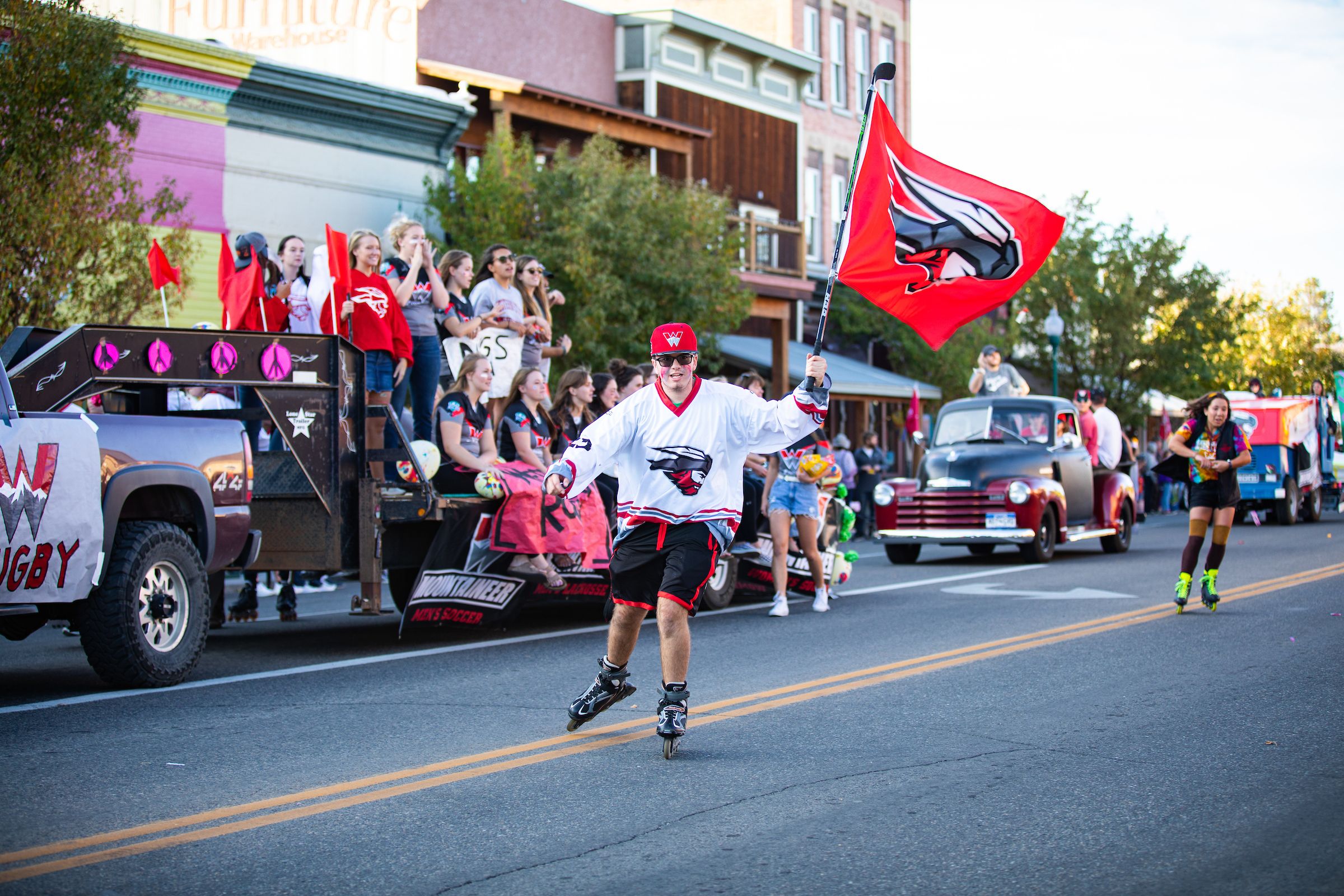 A student roller blades while holding a flag during the Western Colorado University homecoming parade in Gunnison, Colorado. 