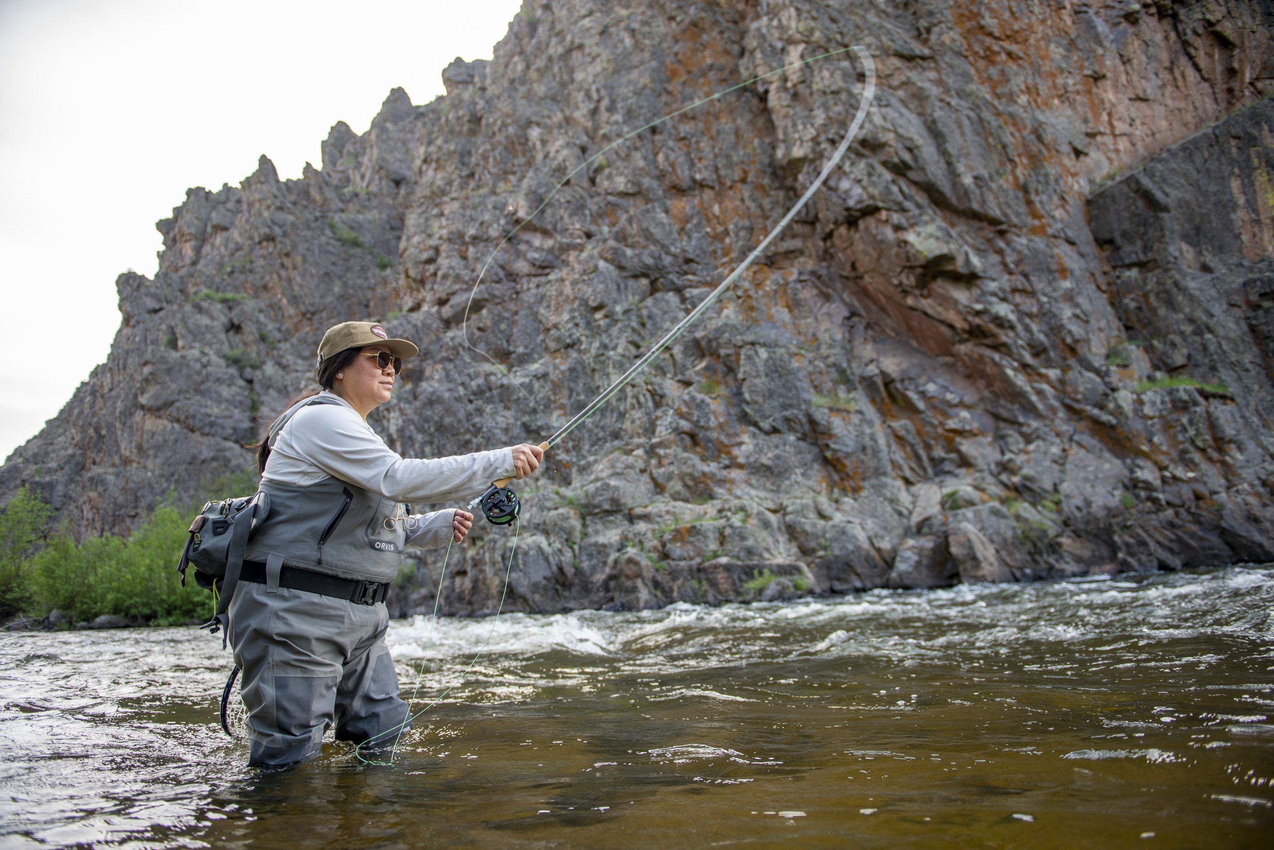 a woman fly fishing in a river 