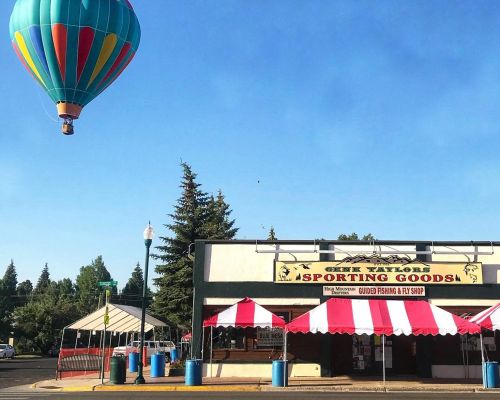 The exterior of Gene Taylors in Gunnison. Striped awnings sit over the door. A hot air balloon is in the sky.