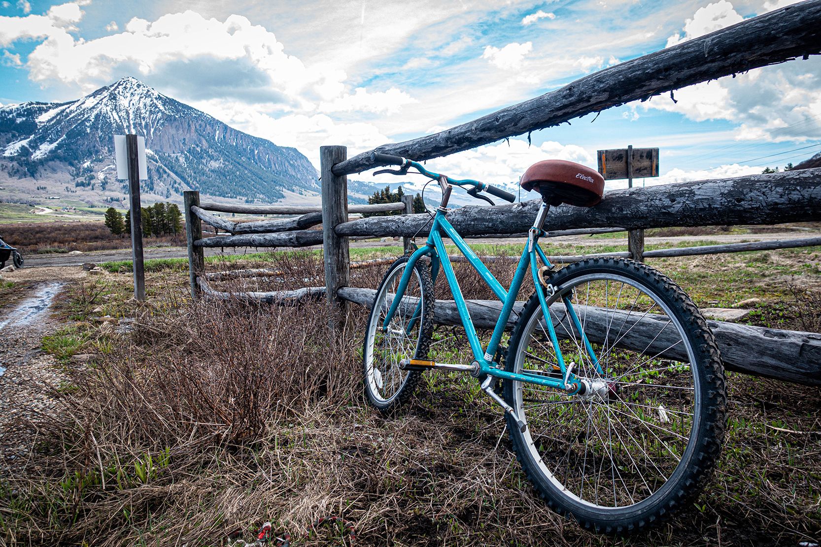 A bike leans against a wooden fence during mud season in Crested Butte.