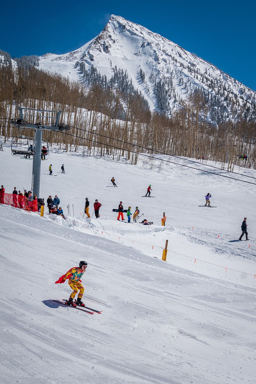 A skier in a costume skis down a groomed slope towards the pond skim at CBMR.