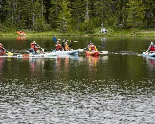 A ground of adaptive kayakers on a lake