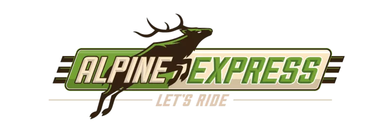 crested-butte-airport-transportation-alpine express. A large bus is parked on a road in front of snowcapped mountain peaks.