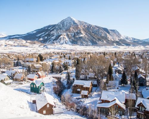 an aerial view of downtown Crested Butte with Crested Butte Mountain, a pointy mountain peak, in the background