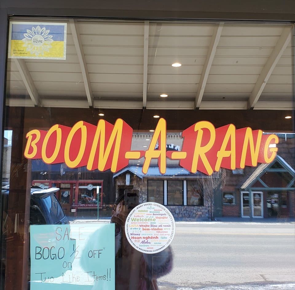 Boom-A-Rang, a thrift store in Gunnison. The picture features art on the walls, couches, a vintage coffeeshop, shelves with knickknacks and lamps.