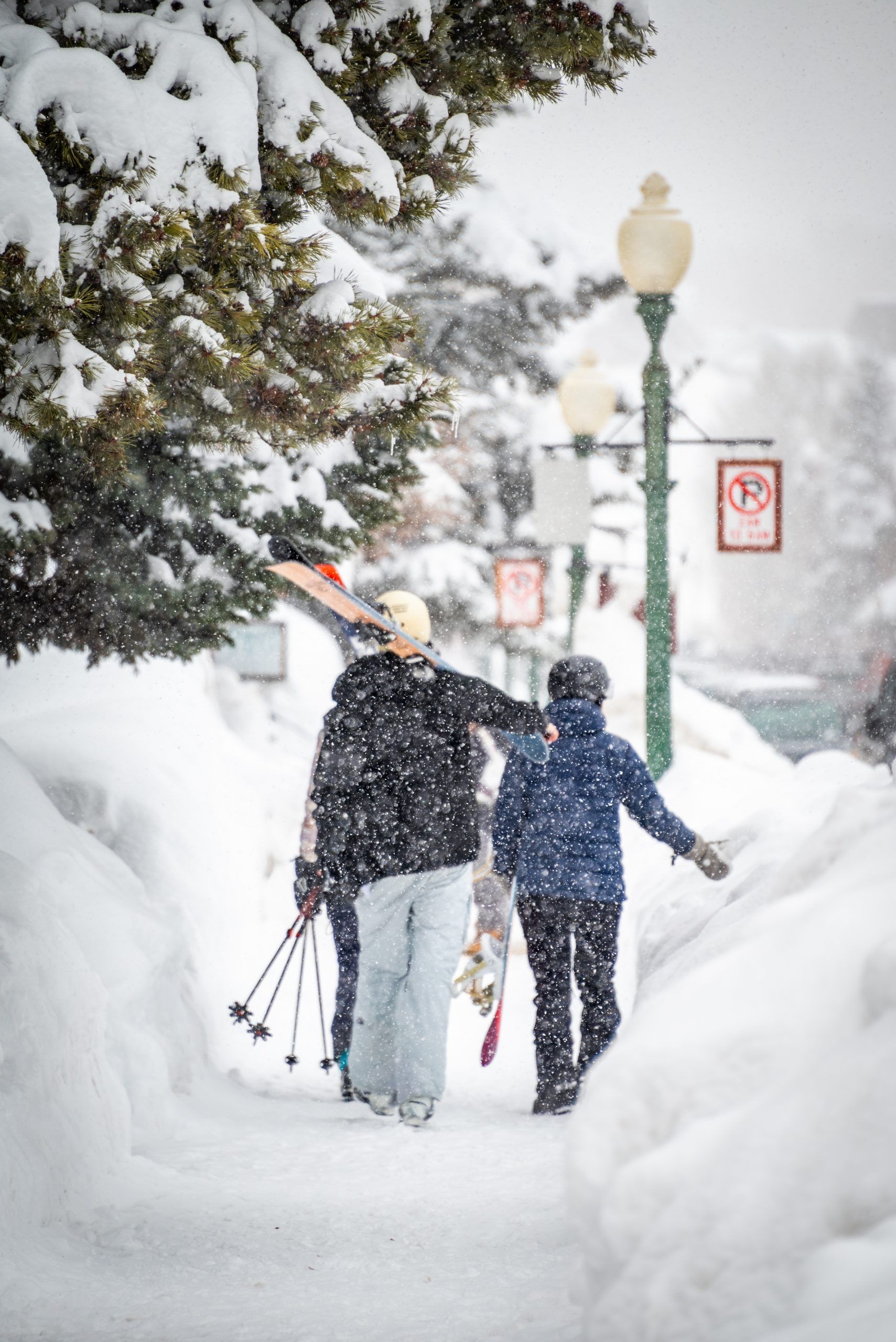 People carrying skis down a snow-lined sidewalk in Crested Butte.