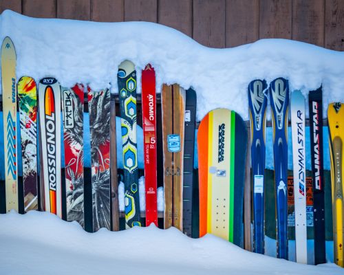 Snowboards and skis lined up in front of a snowbank at cb mountain outfitters