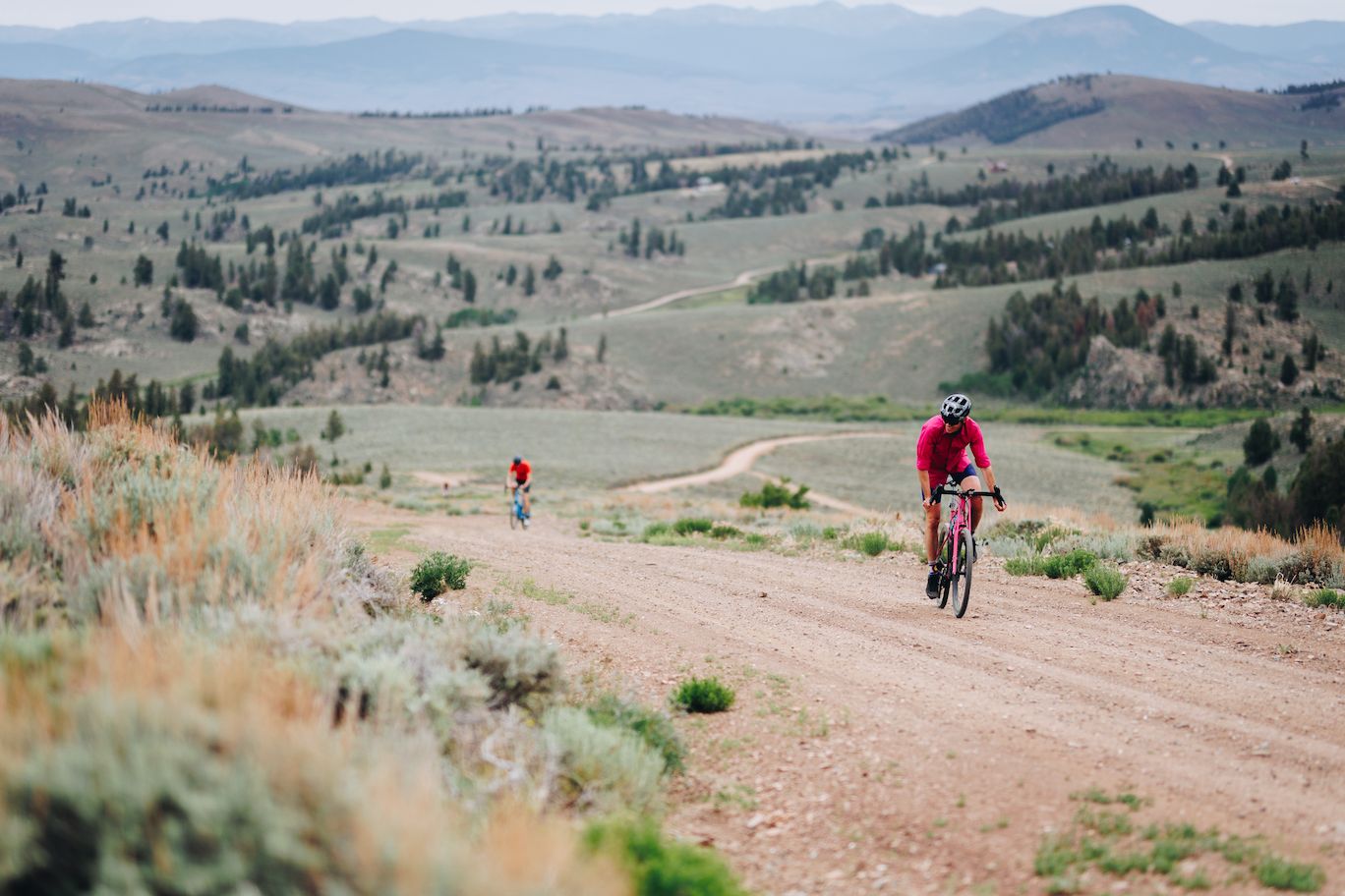 Two people riding bikes on a gravel road