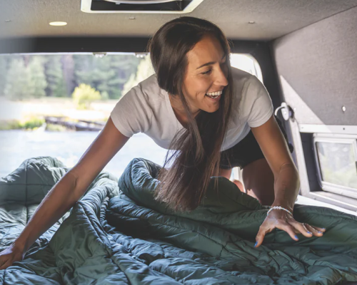 a woman setting up a hest camping mattress in the back of her car