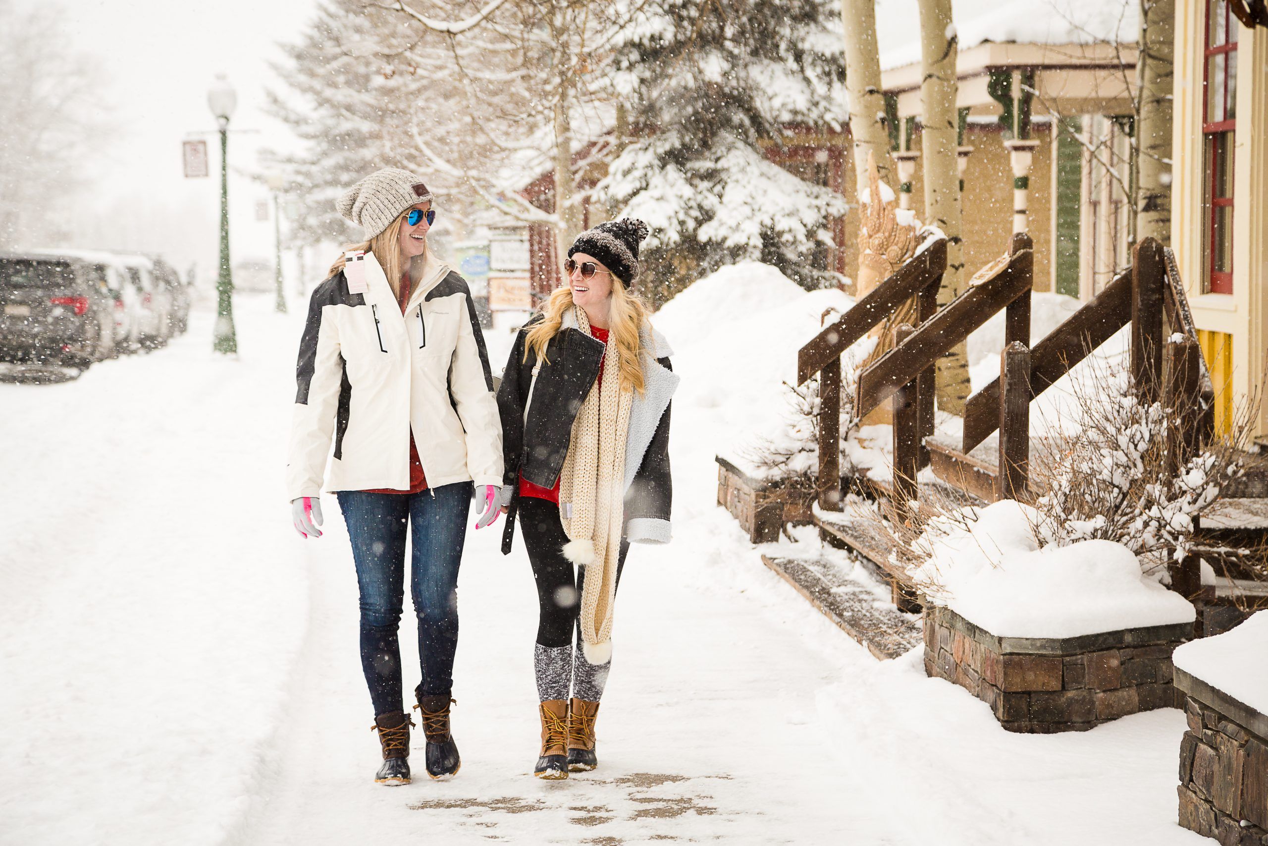 Two women walk down the street in Crested Butte wearing warm winter clothes. 