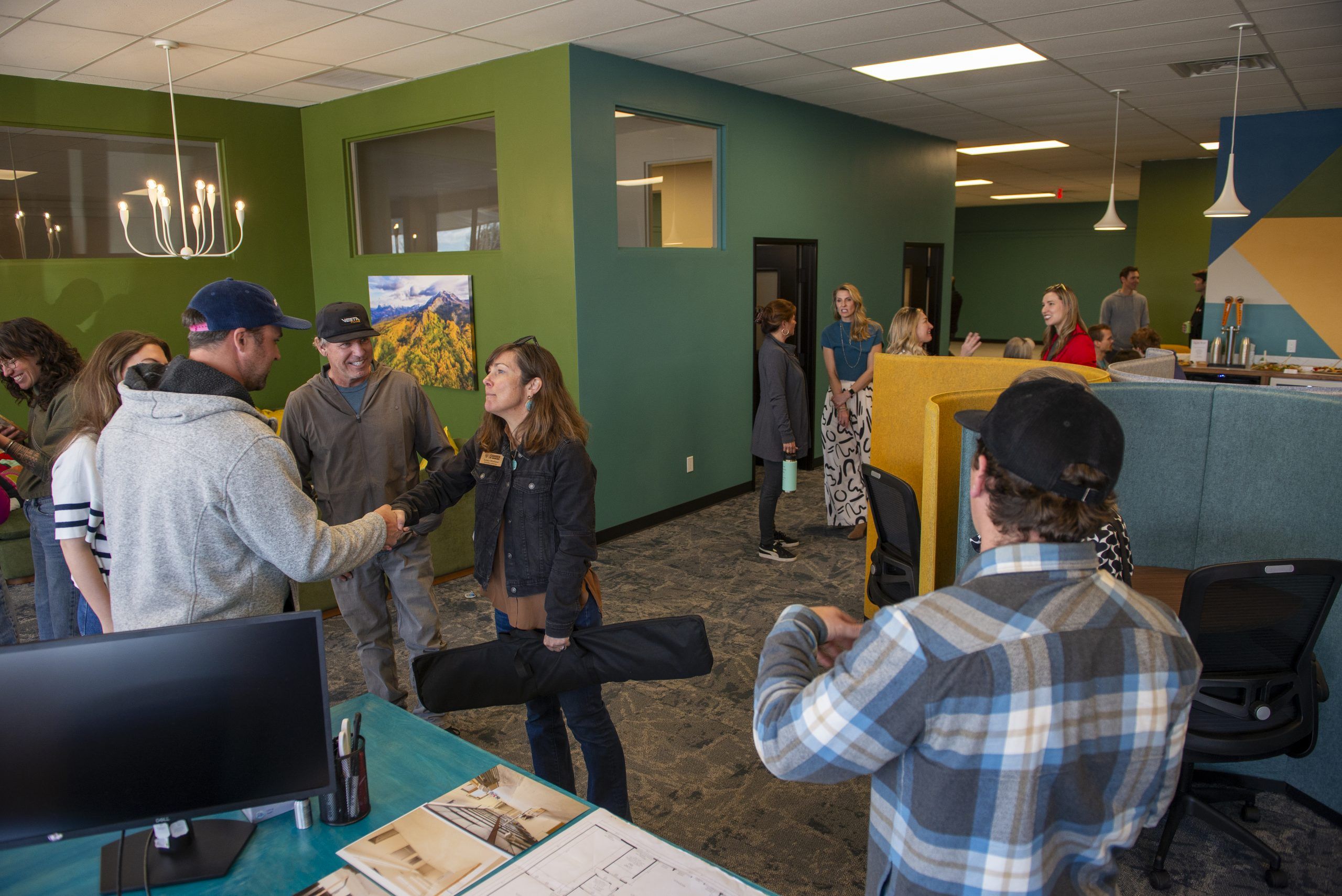 People chat and shake hands at The Hub, a shared warehouse and office space in Gunnison. 
