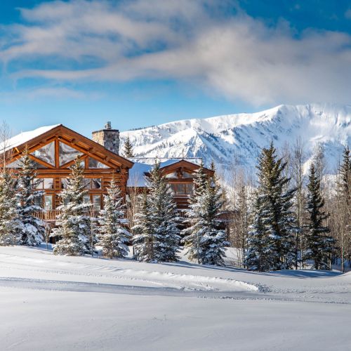 A large home on a snowy hillside with mountains in the background. This is an example of a Mt. Crested Butte lodging property