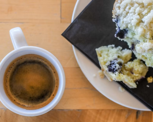 coal breaker coffee. A tabletop view of a coffee mug and crumbly blueberry muffin sitting on a plate.