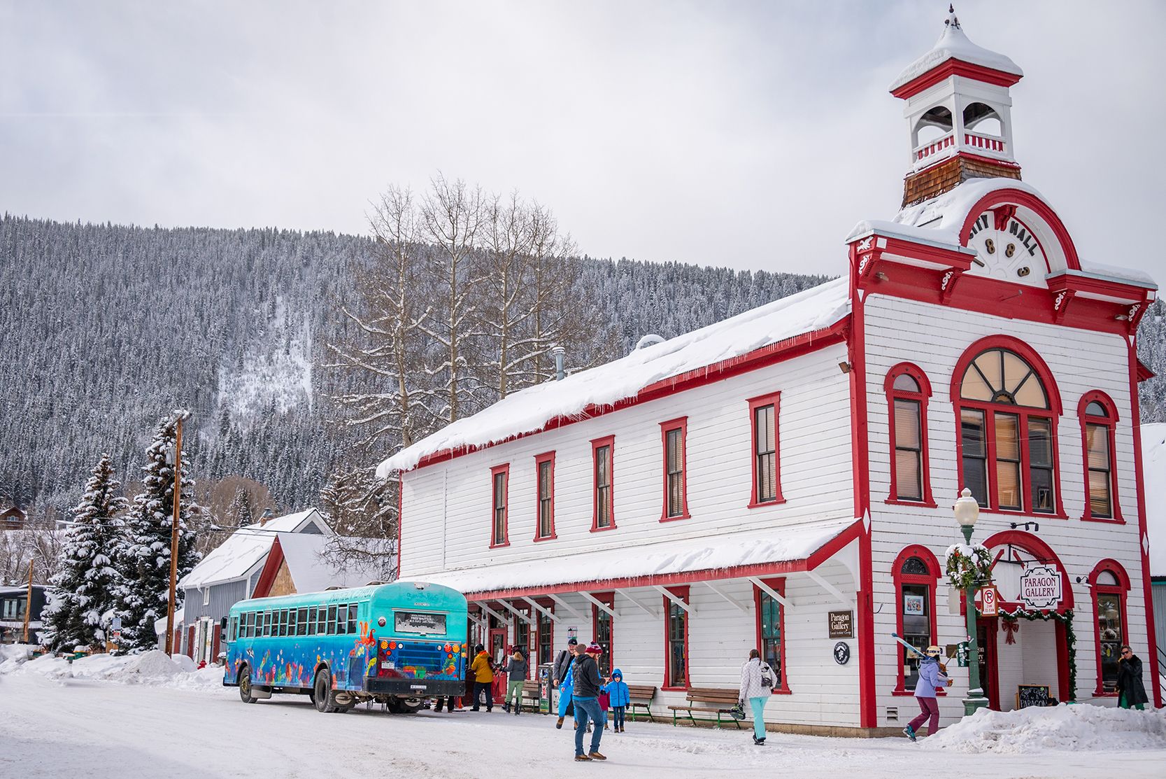 A blue bus stops outside the red and white historic town hall in downtown Crested Butte in winter. 