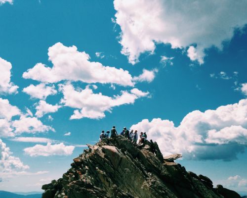 climbing a summit under partly sunny skies