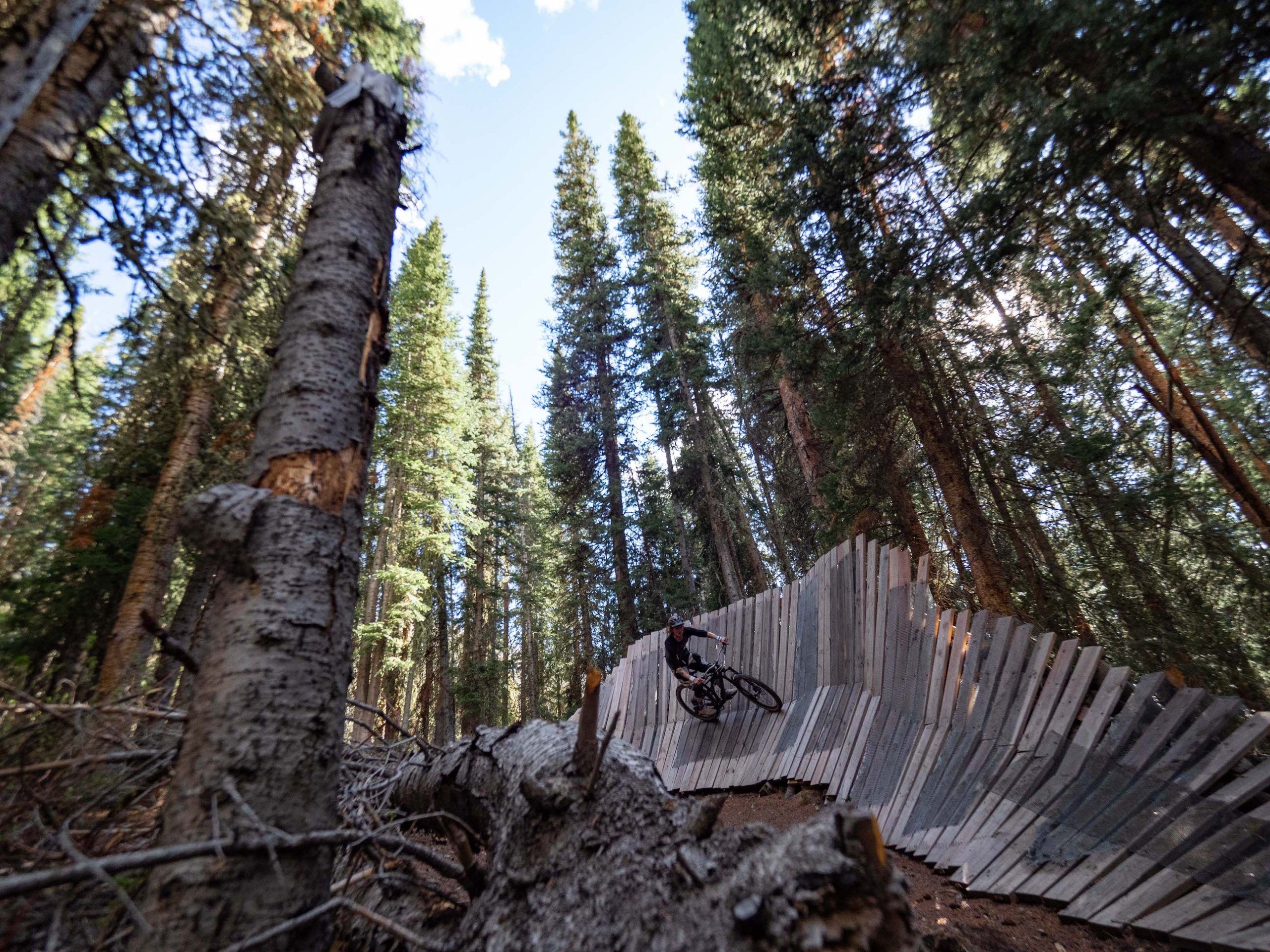 A difficult bike trail at the Crested Butte bike park. A mountain biker rides on a wooden trail