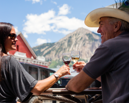 Two people drink wine at a restaurant on a summer day in Crested Butte.