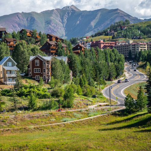 Large vacation rentals on a hillside with a mountain peak in the background. These properties are mt. crested butte lodging