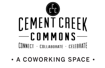 Two people sitting in separate booths on their laptops at Cement Creek Commons coworking space in CB South. A window is to the right.