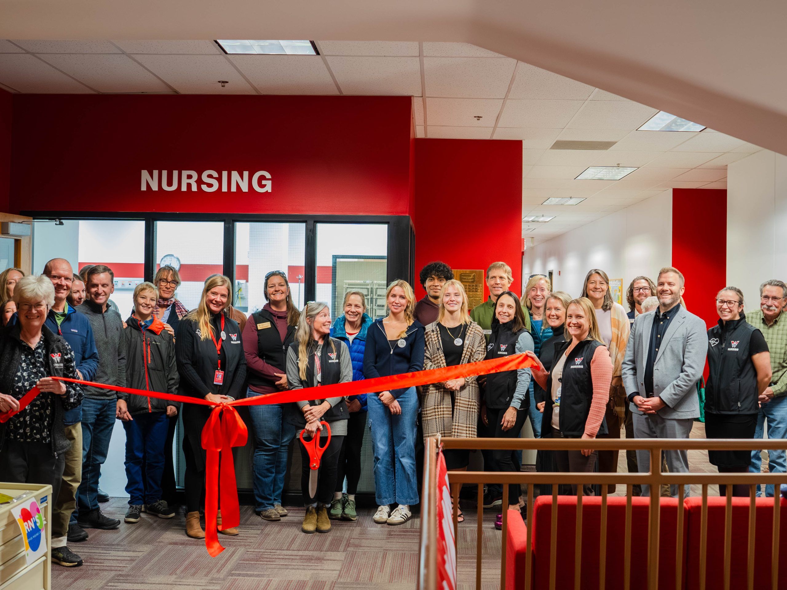 Staff smile for a photo in front of the new sign for the nursing program at Western Colorado University.