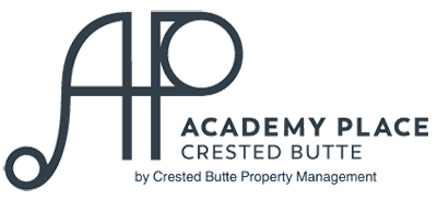 A property with Crested Butte Property Management. The vacation rental has a small yard with a porch, seating, flowers and trees.