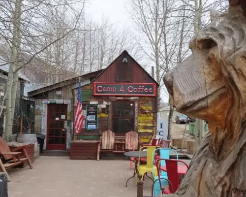 Camp 4 Coffee in Crested Butte, CO. The small building has a tall, pointed roof, two doors and license plates on the front of the building. A sign that says "Camp 4 Coffee" resides above the door.
