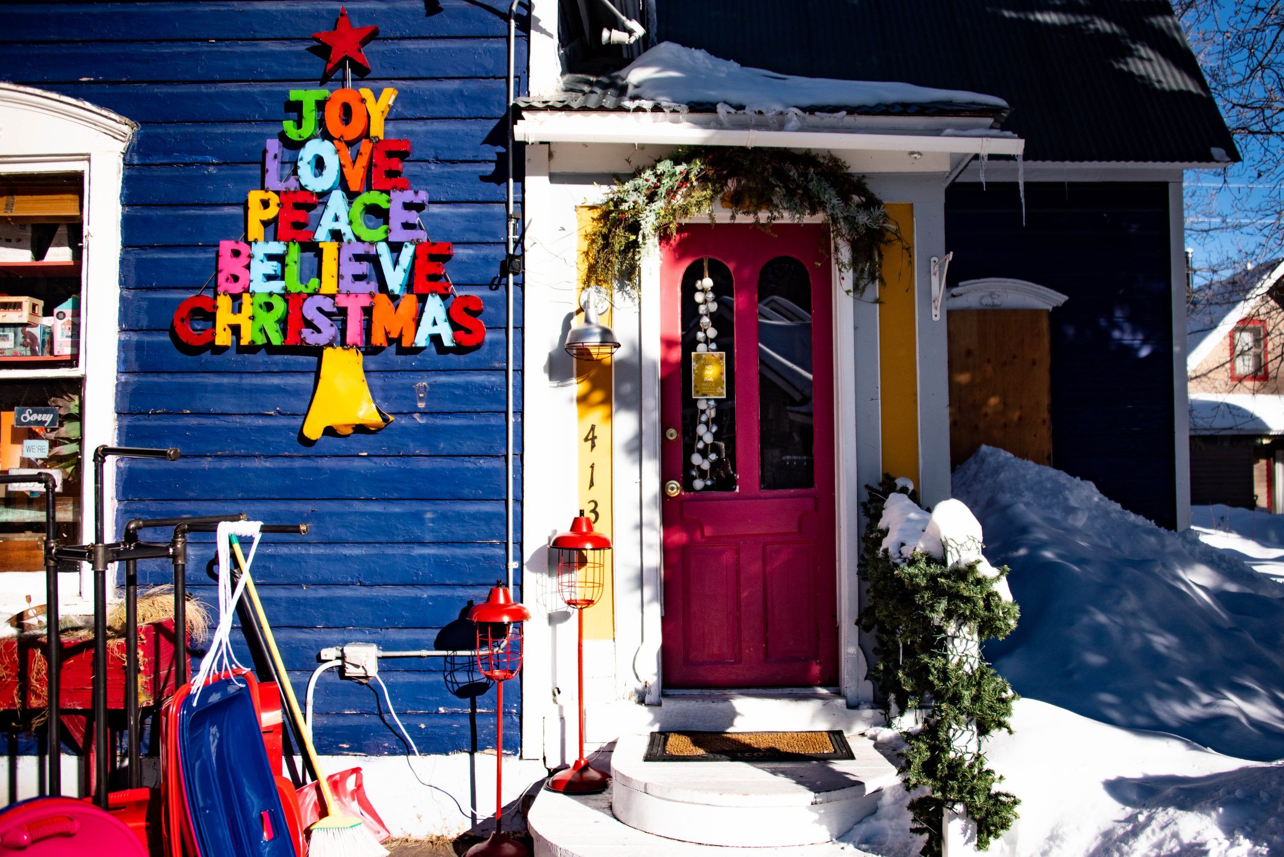 A red door on a blue house in Crested Butte covered in Christmas decorations.