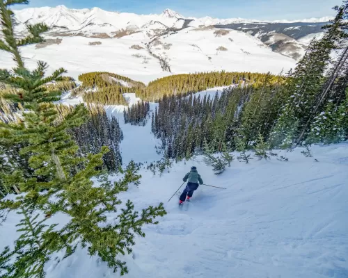 A skier on a steep snowy slope
