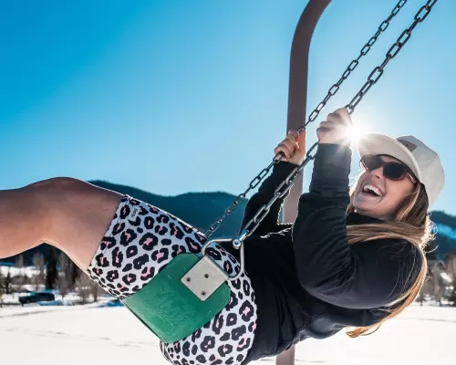 a woman on a swing wearing a pair of buttnski shorts. the shorts go just above the knee and feature a spotted pattern that resembles an animal print