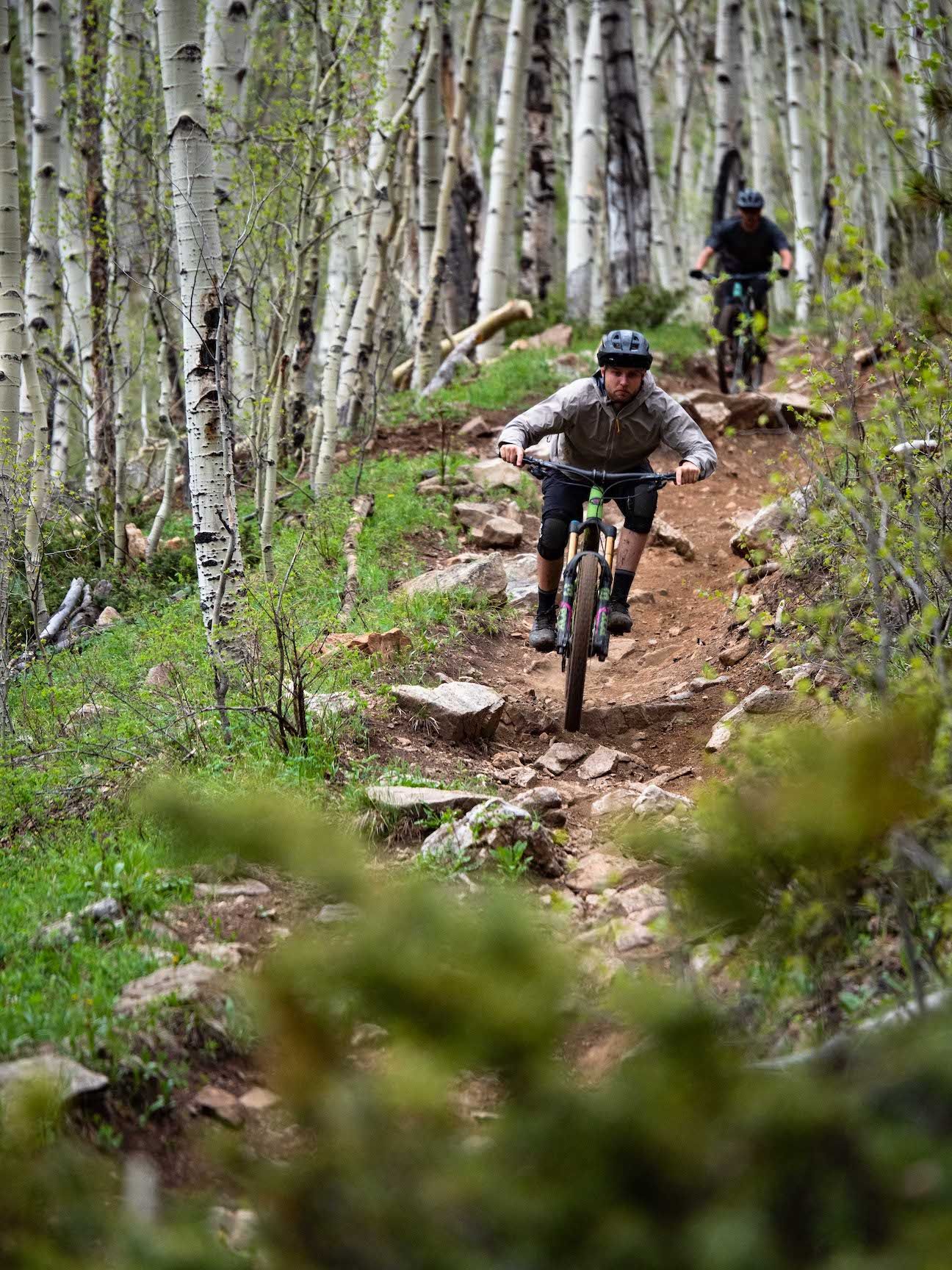 people mountain biking down a steep trail. Doctor Park is a famous MTB trail in Colorado