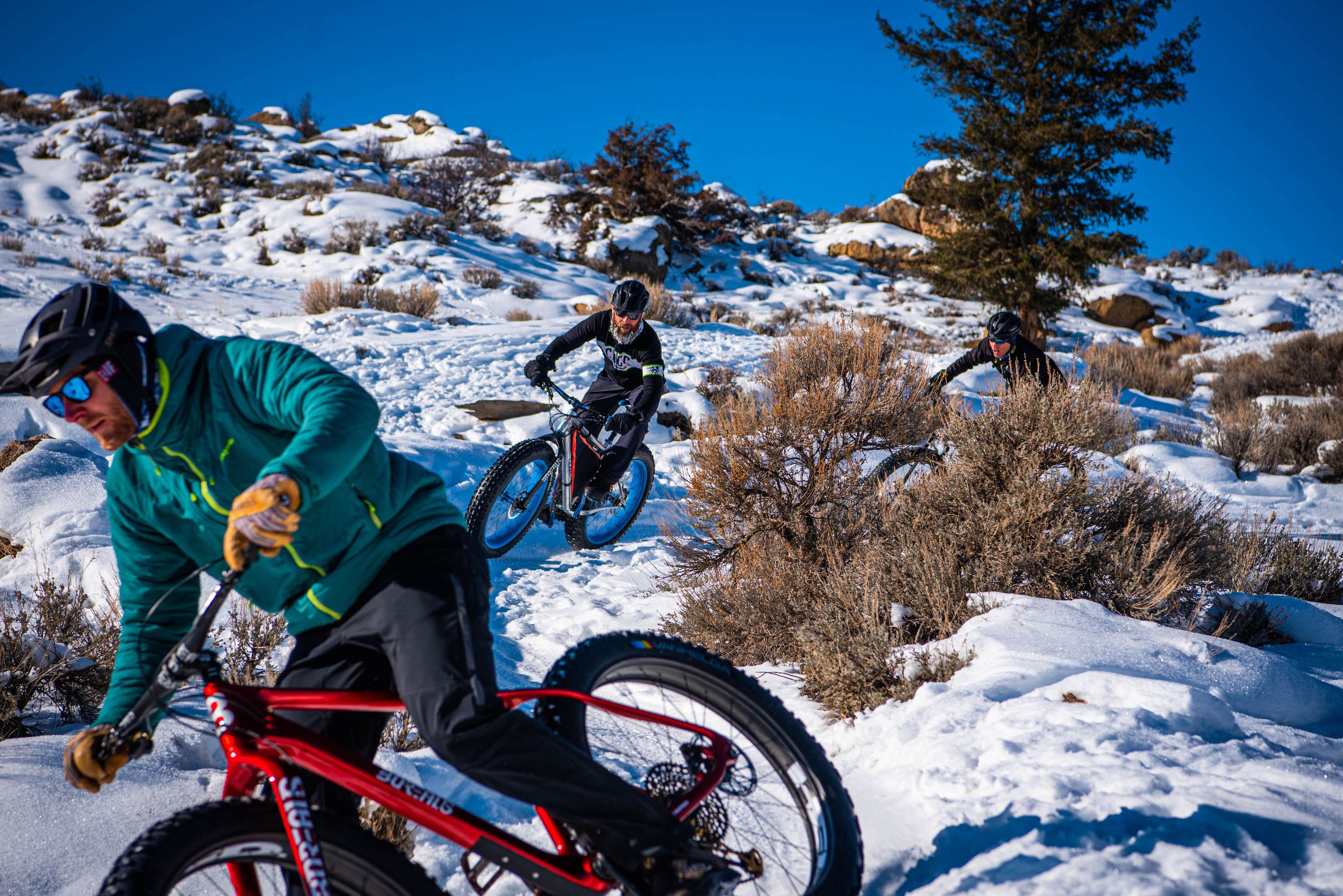 two mtb riders making their way down snowy trail