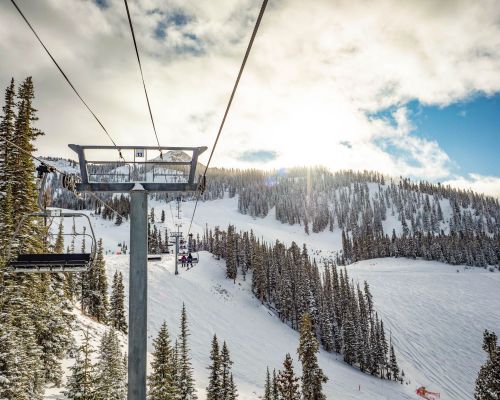 The view from a chairlift overlooking ski runs and a mountain peak