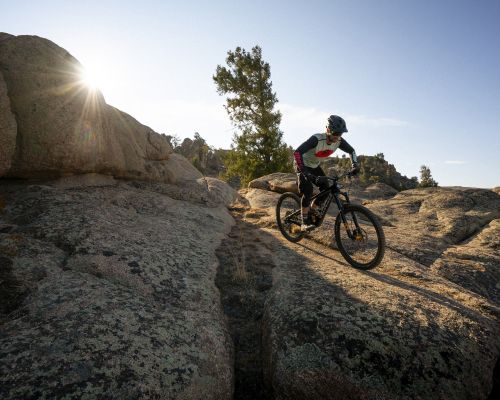 A man mountain bikes over rocks at sunrise at Hartman Rocks in Gunnison, Colorado.