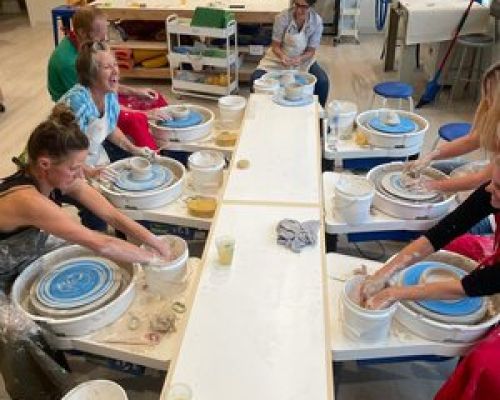 A class at Crested Butte Clay Studio. Six people sit around pottery wheels arranged in a circle.