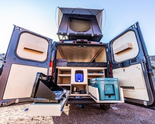 a native campervan open in the back to show the bed, storage and kitchen set up