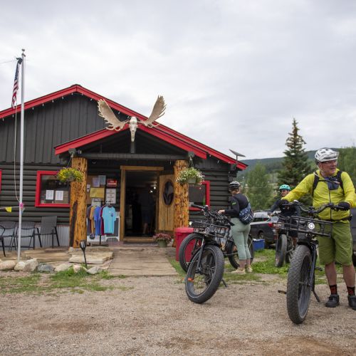 People standing with bikes outside a cabin-style building in Pitkin, Colorado
