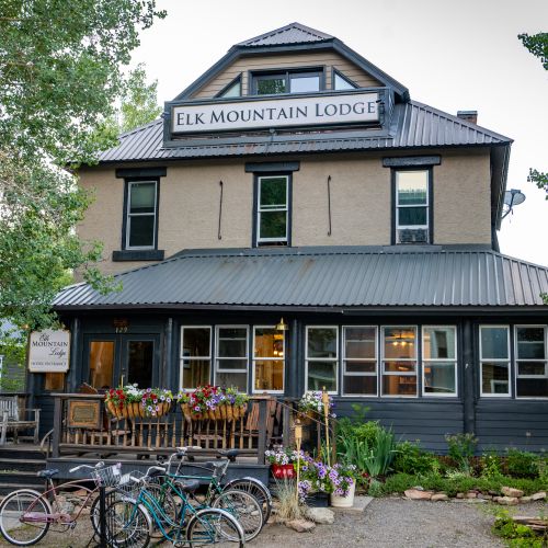 A lodge-style hotel with a bike rack and flower pots on the porch. This is one of the Crested Butte lodging options