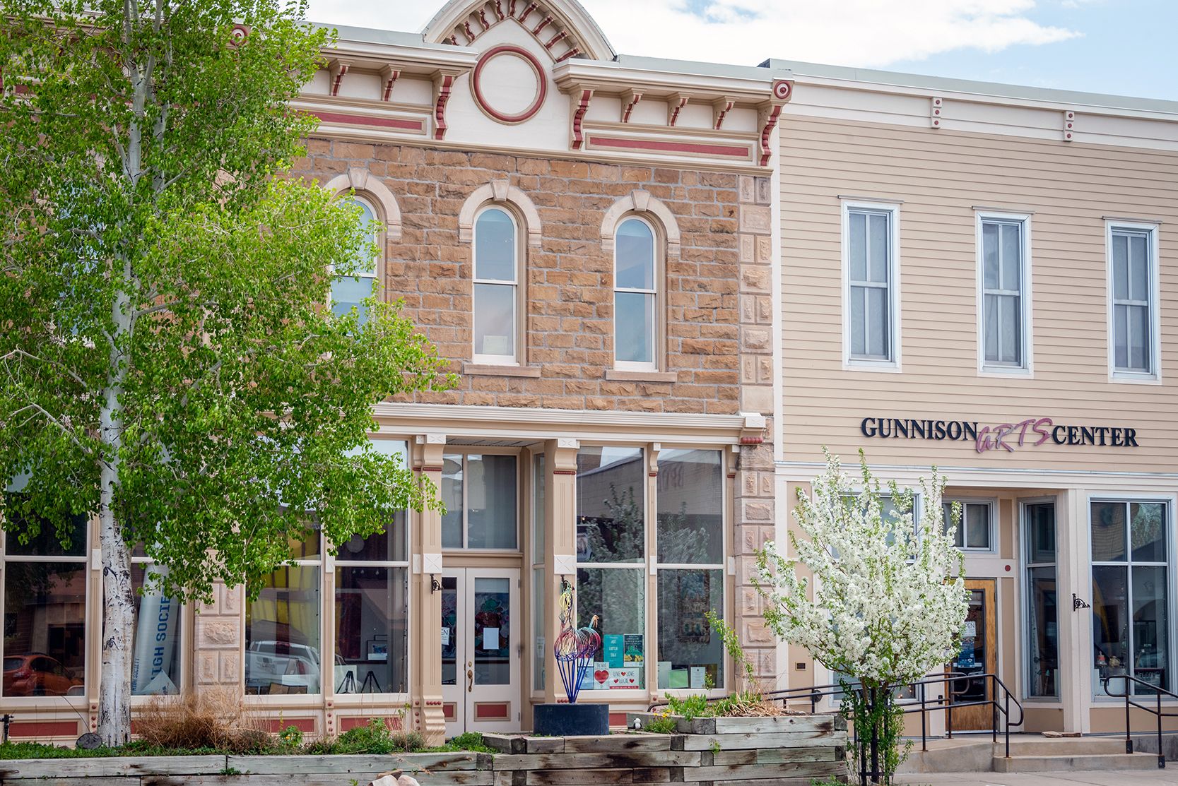 Green leaves and white flowers adorn the trees in downtown Gunnison on a spring day.