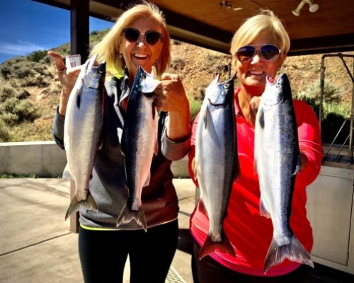 two women stand next to each other holding up two fish apiece after a day of fishing with Blue Mesa Fishing.