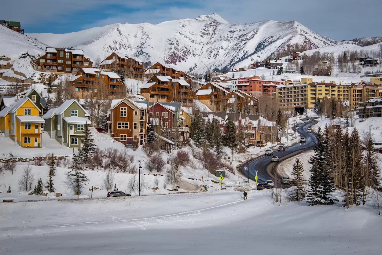 A scene of hotels and vacation rentals with snowy mountain peaks in the background
